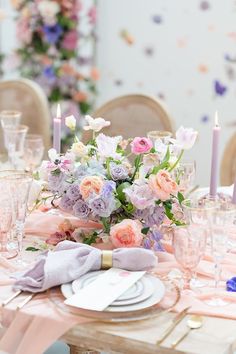 the table is set with pink and purple flowers