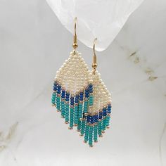 a pair of beaded earrings with blue and white beads hanging from it's earwires