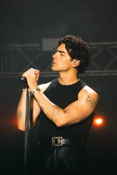 a man with tattoos on his arm holding a microphone and looking up at the sky