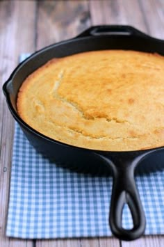 a skillet filled with cornbread sitting on top of a blue and white checkered cloth