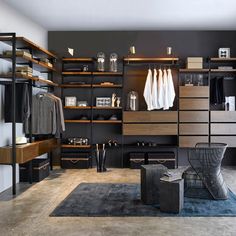 a large walk in closet with lots of shelves and clothes hanging on the walls, along with a blue rug