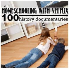 two young children laying on the floor playing with a remote control in front of a television