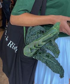 a person wearing an apron holding a bunch of broccoli