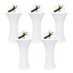 four white pedestal tables with wine glasses and flowers on each one, set against a white background