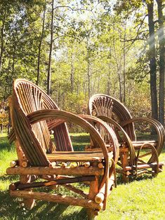 three wooden chairs sitting on top of a lush green field