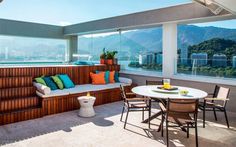 an outdoor living area with wooden furniture and large windows overlooking the cityscape in the distance