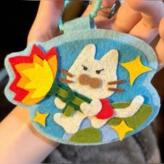 a hand holding a hello kitty keychain with stars and a rocket on it