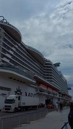 a large cruise ship docked at the dock with people standing around and looking at it