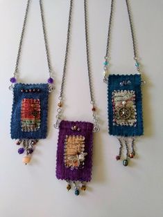 three different necklaces hanging from chains on a wall