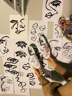 a person is drawing faces on paper with scissors and tape to make them look like they are holding up their shoes