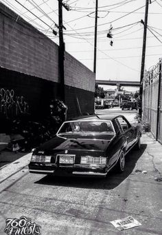 a car parked on the side of a road next to a wall and power lines