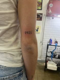 a woman with a small tattoo on her arm that reads 1911, in black ink