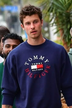 a man in a blue sweatshirt is walking down the street with other people behind him