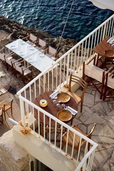 an outdoor dining area next to the ocean with tables and chairs set up on it