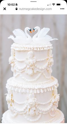 a white wedding cake with two swans on top