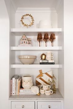 a white shelf filled with books and cups