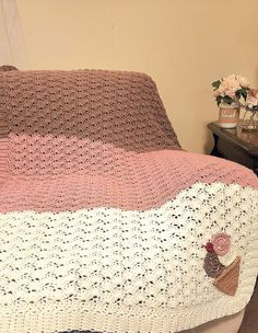 a crocheted blanket is sitting on top of a bed with flowers in the corner