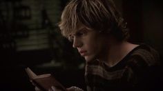 a young man is reading a book in the dark