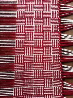 red and white woven material with fringes on it's sides, sitting on a table