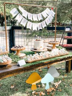 an outdoor dessert table with cupcakes and cakes on it, along with bunting banners