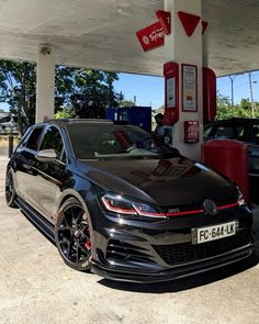 a black volkswagen car parked at a gas station