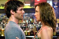 a man and woman standing next to each other in front of a bar at night