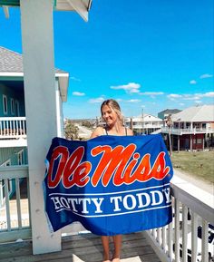 a woman standing on a porch holding a blue towel with the word mississippi in red and orange