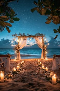 an outdoor wedding set up on the beach with candles and flowers in front of it