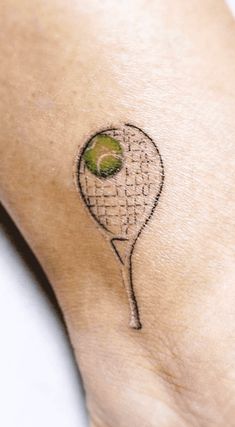 a tennis racquet with a green ball on it's back side tattoo