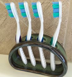 four toothbrushes are in a holder on the wall, one is blue and white