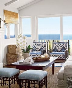 a living room filled with furniture and a large window overlooking the ocean in front of it