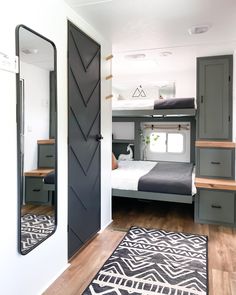 a bedroom with a bunk bed, mirror and rug on the floor in front of it