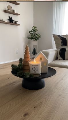 a candle is sitting on top of a table in front of a couch and christmas tree