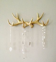 a gold deer antler rack with crystal beads hanging from it's sides on a wall