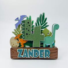 a wooden sign that says zander with dinosaurs and plants