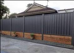 a house with a fence that is made out of wood and concrete, next to a yard