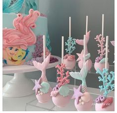 there are many little mermaids on the table and cake pops in the shape of seashells