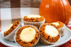 three muffins on a white plate with butter in the middle and an orange pumpkin behind them