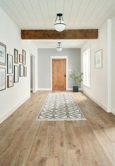 an empty room with wood floors and pictures on the wall, along with a rug