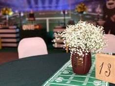 a football themed centerpiece with baby's breath flowers on the table at a sports event