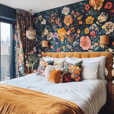 a large bed sitting next to a window in a room with flowers on the wall