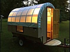 a small house with a glass roof on the back of it's trailer parked in a field