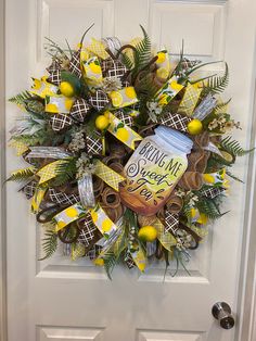 a wreath on the front door decorated with yellow and brown decorations, pineapples, lemons and cinnamon sticks