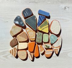 several different colored rocks arranged in a circle on a white wooden surface with wood planks behind them