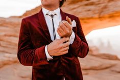 a man wearing a red velvet suit and white shirt with his hands in his pocket