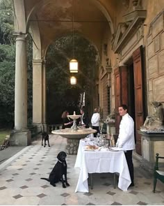 a black dog sitting on the ground next to a table