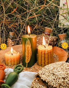 three candles sitting on top of a table next to bread and other items in front of them