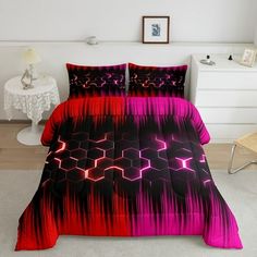 a bed covered in pink and black comforter next to a white table with a chair