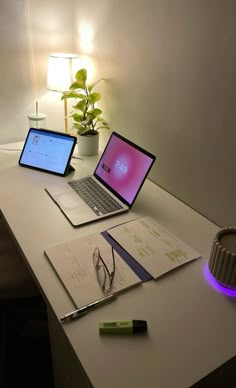 three laptops are sitting on a desk next to a lamp and some papers with pens