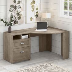 a computer desk with a laptop on top of it next to a lamp and window